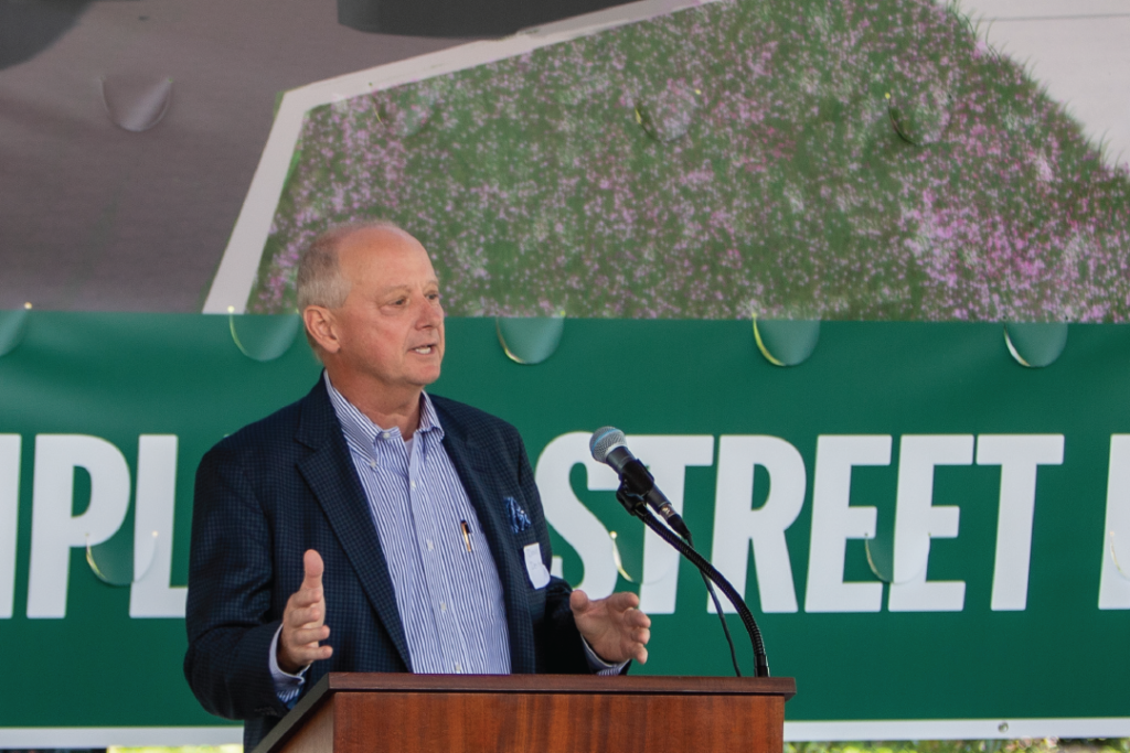 DDA Chair Dave Deiters announce Shop Local Throw Down in front of Complete Street Groundbreaking banner.