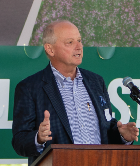 DDA Chair Dave Deiters announce Shop Local Throw Down in front of Complete Street Groundbreaking banner.